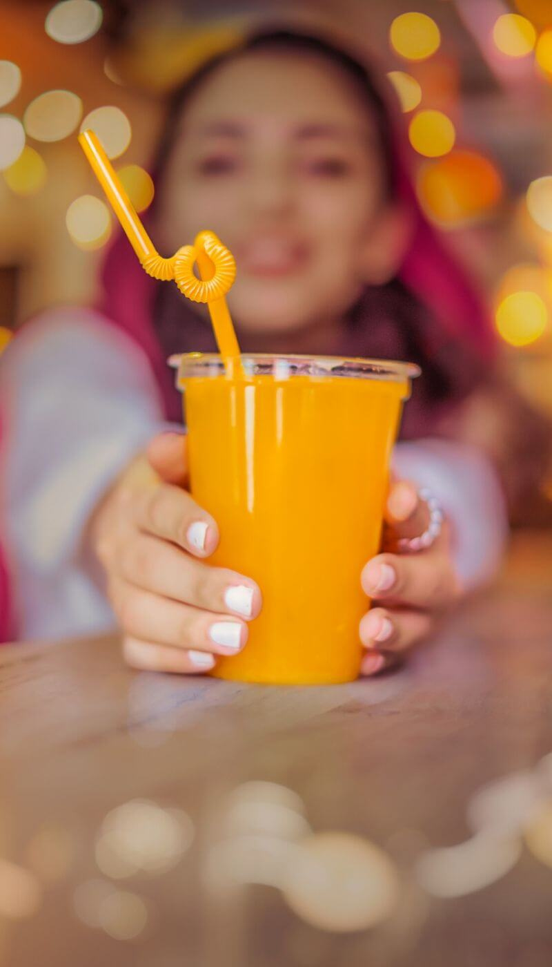 Lány narancslét nyújt felénk.