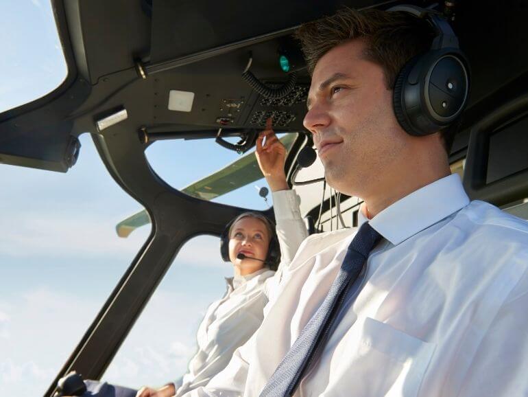 Egy férfi és egy női pilóta fehér ingben a vezérlőpult előtt.